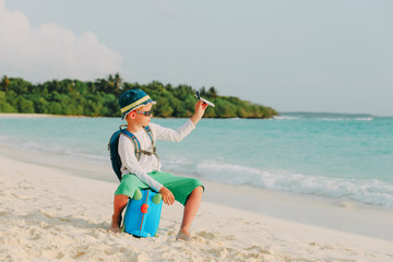 travel to beach-little boy with toy plane, backpack and luggage at sea