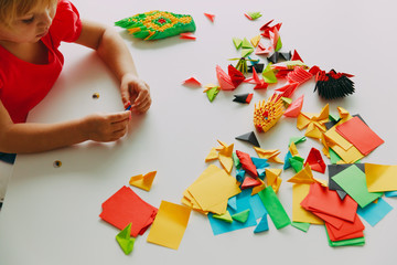 little girl making origami crafts with paper