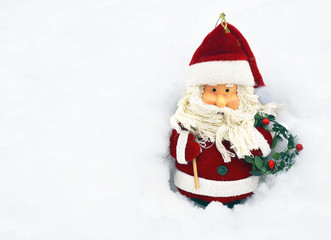 Christmas decoration.Santa Claus figurine on natural snow background with space for text.Selective focus.