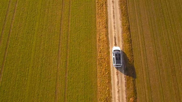 White minivan car driving beside farm fields top view drone shot 4K