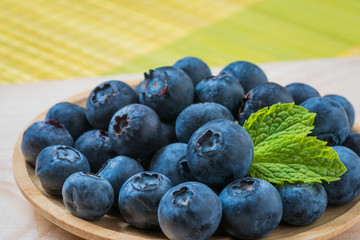 Arrangement blueberries in container on wooden plank, Closeup mint with blueberries