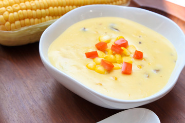 Corn soup and tomato in white bowl on  wooden background.closeup