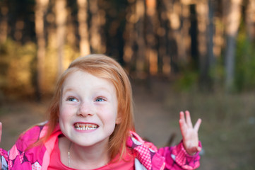 Red-haired girl showing teeth in the forest