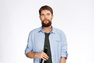 Young guy with a beard on a white isolated background holds a bottle of beer