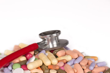 pile of colored pills and a stethoscope isolated on a white background