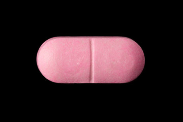 close-up of a pink pill isolated on a black background.psd