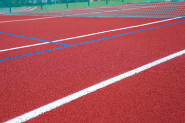 Red tennis court with tennis ball, artificial cover ,close up.