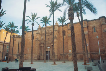 Cathedral of Almeria (Cathedral of the Incarnation of Almeria) and tall palms at the square near it in the evening, Spain.