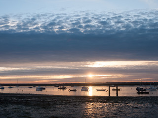 Obraz premium sun set sky dramatic clouds sea front beach harbor marina boats moored landscape