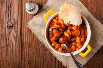 Baked beans in tomato sauce served in yellow, clay bowls.