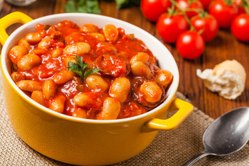 Baked beans in tomato sauce served in yellow, clay bowls.