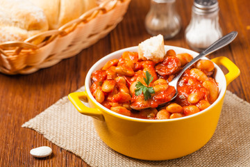 Baked beans in tomato sauce served in yellow, clay bowls.