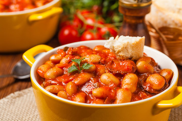 Baked beans in tomato sauce served in yellow, clay bowls.
