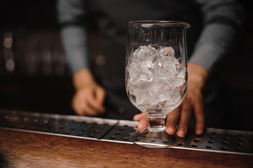 Barman holding a glass filled with ice cubes