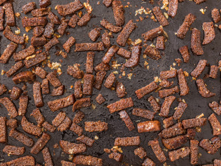 Rye crackers. Rye croutons in oil with garlic on a black background. The view from the top