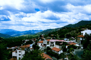 The landscape offers a view of the mountains, the forest and a small village with red roofs. Cyprus, Troodos