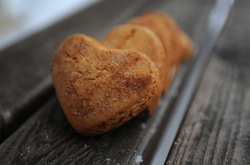 Homemade cookies with sugar and cinnamon in the form of hearts on a wooden background