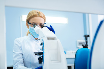Making genetic discovery. Concentrated blond young promising researcher wearing a uniform and a...