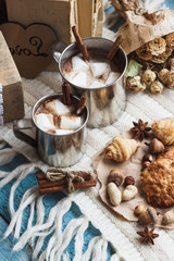 Metal cups with cacao and marshmallow and different cookies