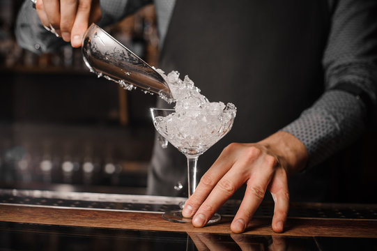 Barman putting ice into the cocktail glass