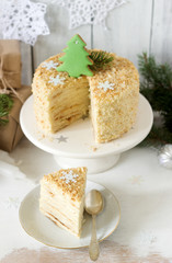 A piece of Napoleon cake in Christmas or New Year decoration on a light background. Rustic style.