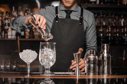 Bartender making a cocktail with help of the bar equipment