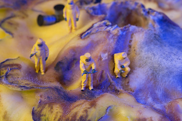 Fototapeta premium The ecologists or technicians or cleaners on a organic surface with fungus, which looks like a surface of another world or a planet with a crater. Environment pollution concept. Selective focus.