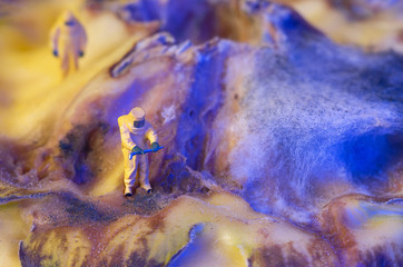 The ecologists or technicians or cleaners on a organic surface with fungus, which looks like a surface of another world or a planet with a crater. Environment pollution concept. Selective focus.