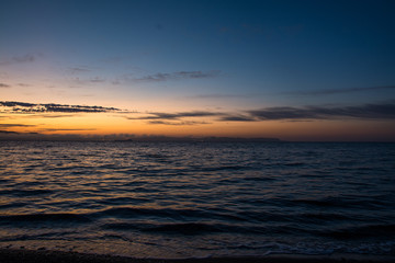 Fototapeta na wymiar Orange Sunset Above Dark Water of Sea.