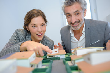 Fototapeta premium Man and woman looking excitedly at housing model