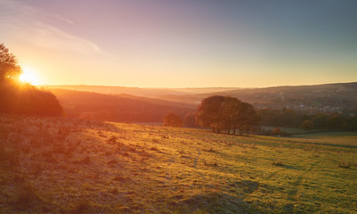 Red, Orange and yellow glow of a sunset over green pastures and trees in the English Countryside. Gibside  near Newcastle upon Tyne.