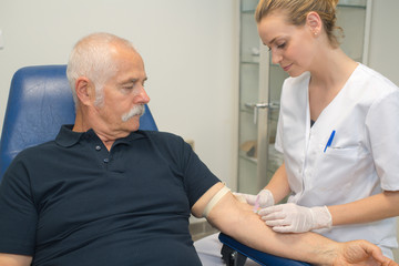 doctor making blood test for senior man