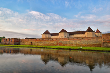Naklejka na ściany i meble Medieval stone fortress on water in sunrise warm light