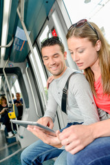 Couple on public transport, looking at tablet