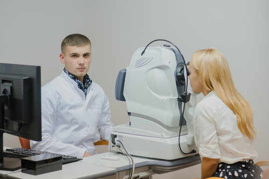 Young beautiful doctor/eye specialist/optometrist in an ophthalmologic clinic dooing a patient a Tomography