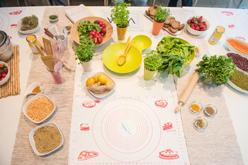 Top view of healthy food ingredients and kitchen utensils for cooking, ready for preparation of vegetable meal, on table