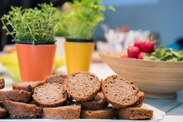 Whole grain sliced bread with radishes and spice herbs in background