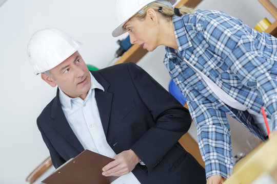 Middle aged people wearing hardhats in discussion