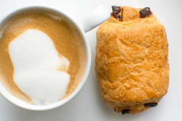 breakfast food on a plate, cappuccino coffee and chocolate croissant