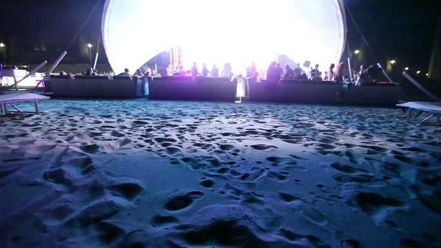Stage and a disco on the beach. Night Beach Disco with illumination. concert. Celebration. holiday. feast. Dancing people with fun gladness on the discotheque entertainment. sandy beach