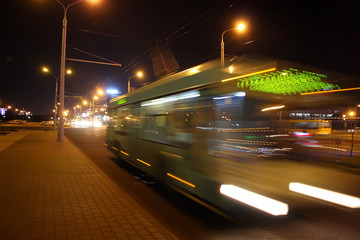 The motion of a blurred trolleybus in the street in the evening