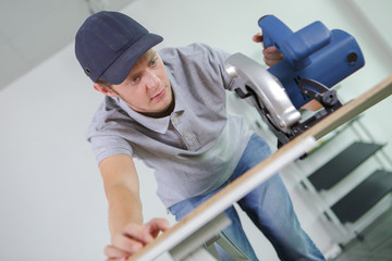 Young man using circular saw on work bench