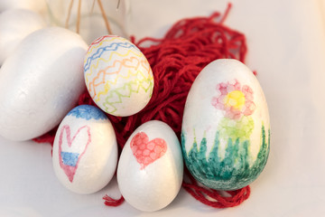 Bunch of white decorated Styrofoam eggs decorated with felt tip pen on red wool