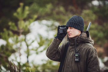 male hunter ready to hunt, holding gun and walking in forest. - obrazy, fototapety, plakaty