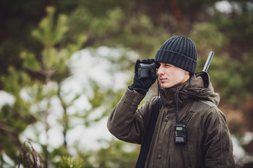 male hunter ready to hunt, holding gun and walking in forest.