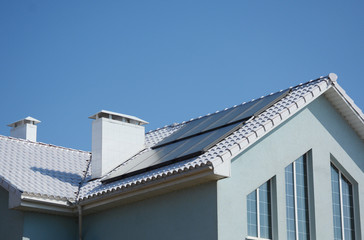 Modern passive house with solar panels and white roof for energy efficiency.