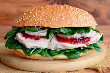 Healthy chicken burger. Homemade chicken burger with spinach and jam on a wooden board. Closeup