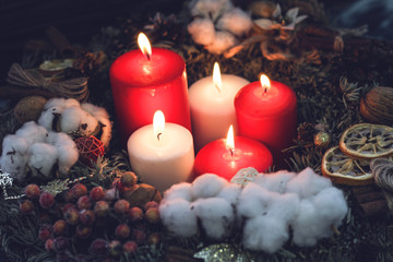 Obraz na płótnie Canvas Red and white burning christmas candles in a wreath with decorations