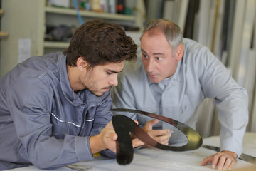 engineer checking trainees work on factory floor