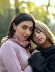 Fototapeta premium Close up portrait of two beautiful young girls on the background of autumn leaves